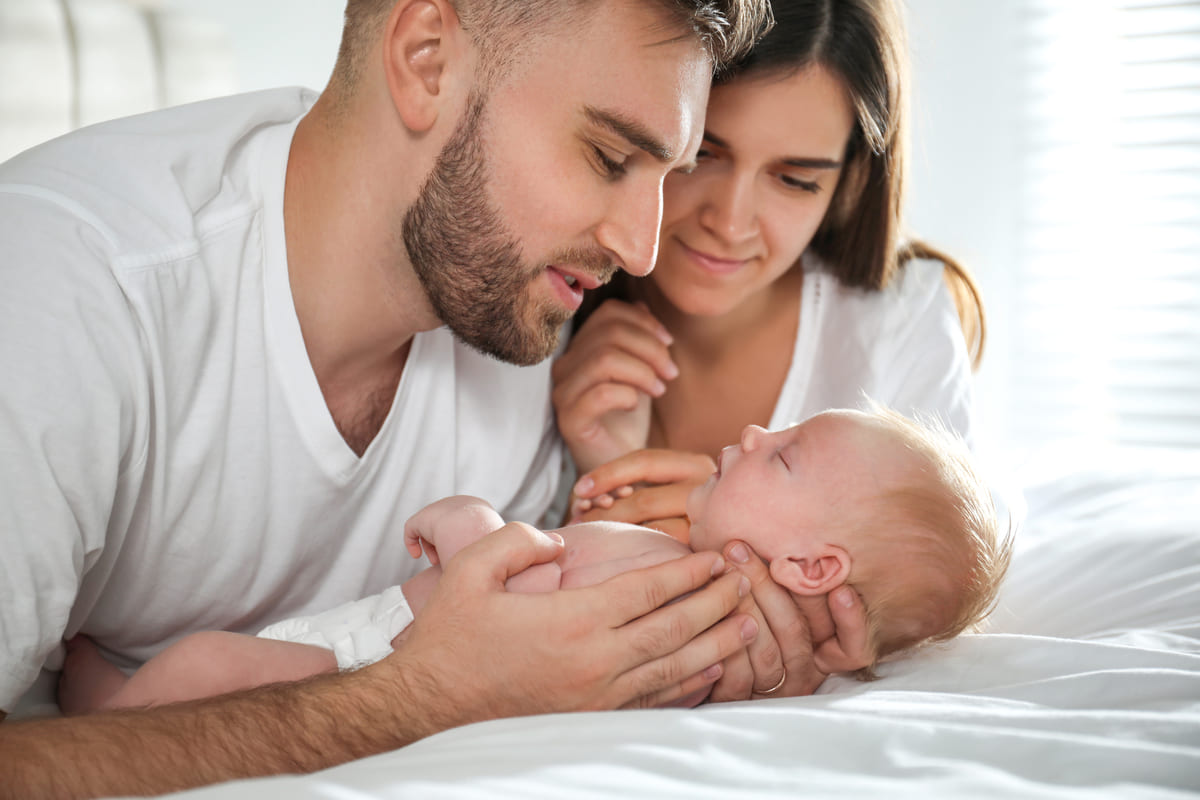 Happy couple with their newborn baby at home.