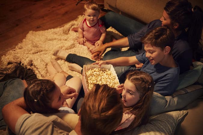family watching movie at home indoors with popcorn.