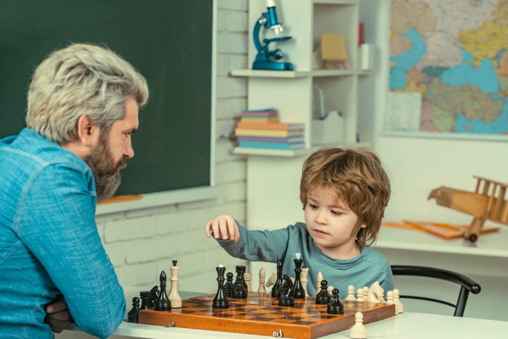 Father playing with son game of chess.