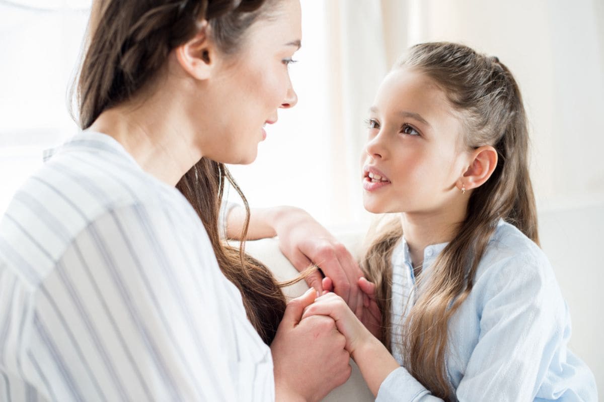 mother and daughter holding hands and talking to each other.