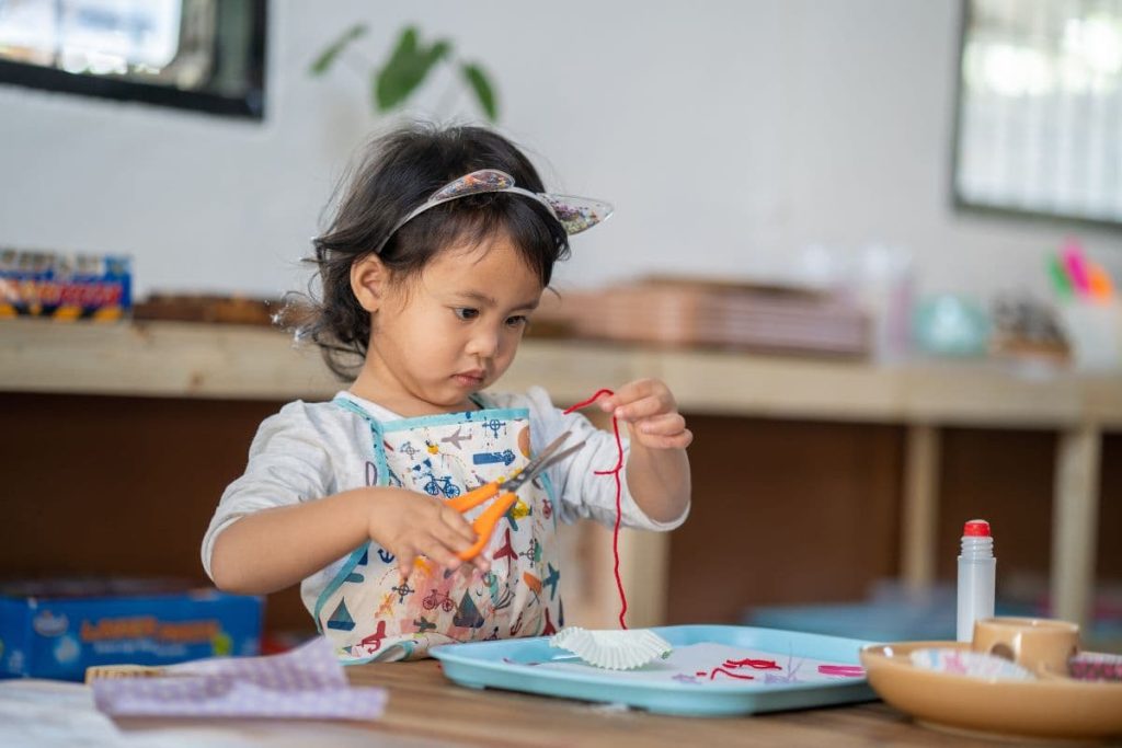 A closeup of a little girl playing with a sewing set.