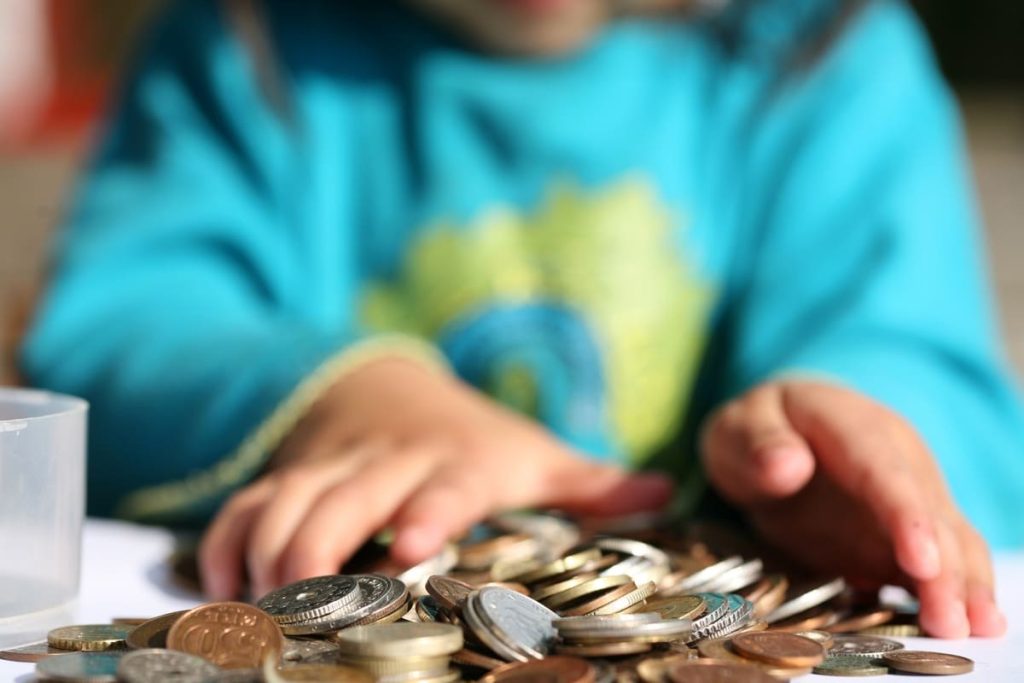 A kid with a pile of money coins.