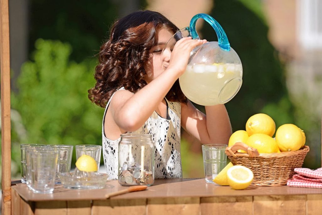 Little girl drinking from lemonade pitcher, kids lemonade stand.