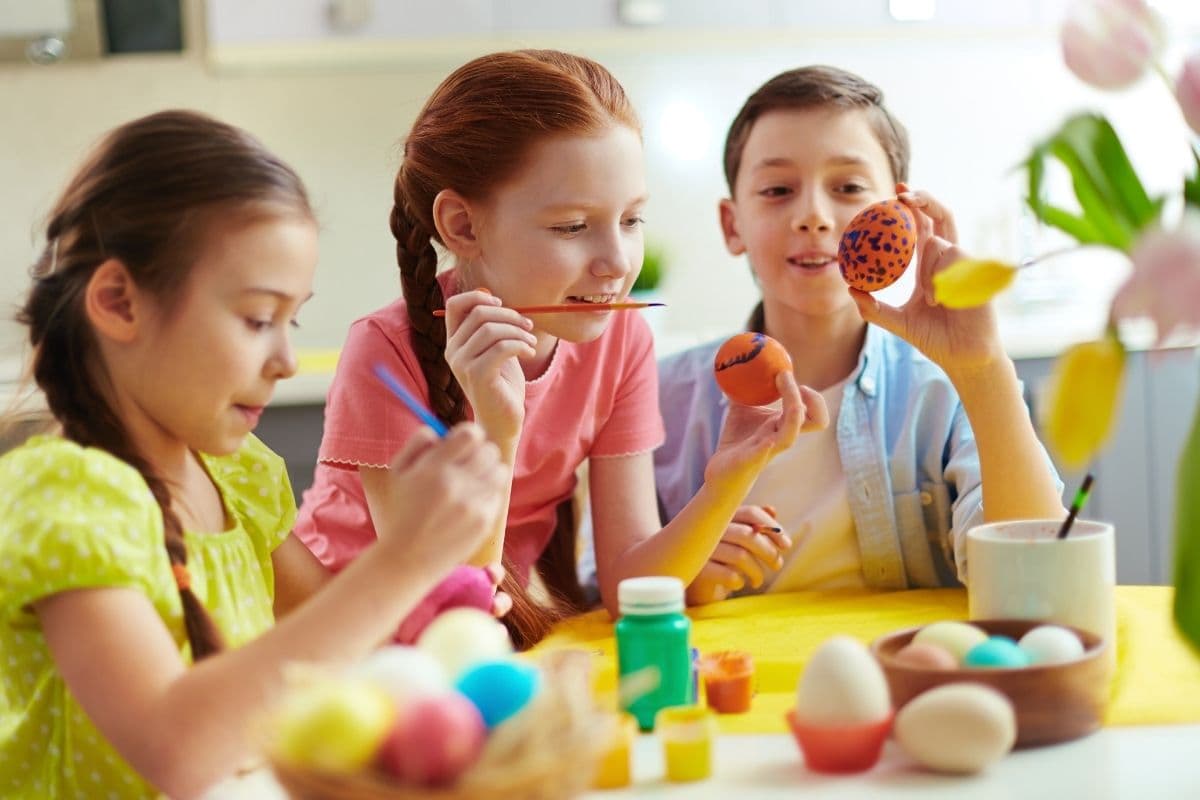 Photo of cute kids painting Easter eggs at home.