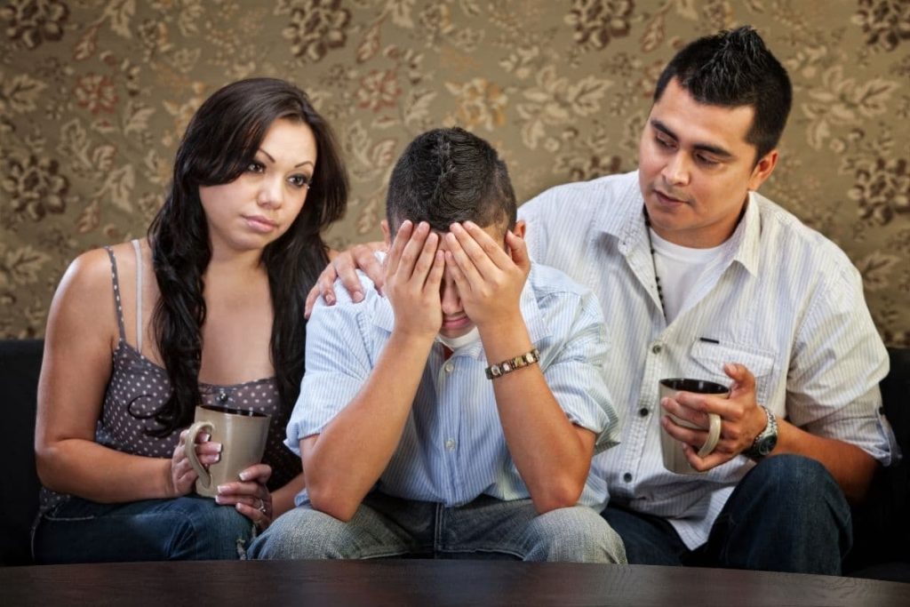 Sympathetic Latino parents with depressed male teenager.