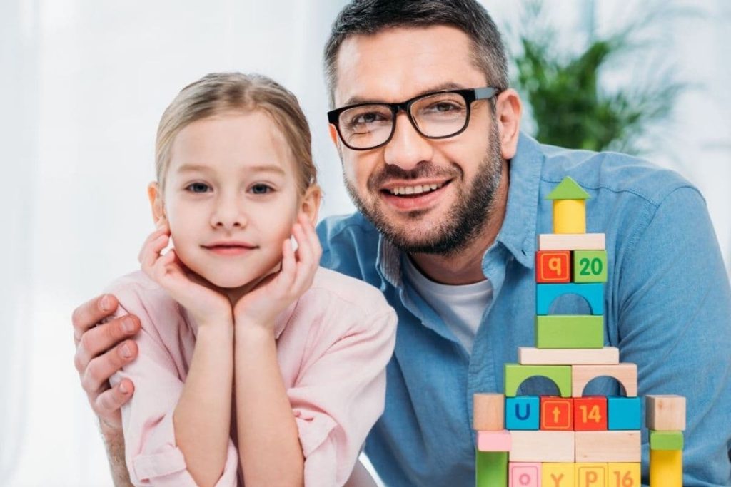 father and daughter with building blocks beside them.