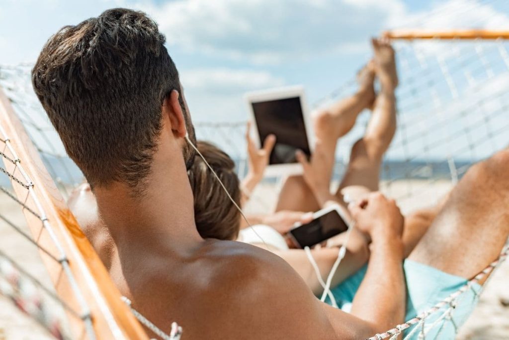man and women on the beach with their gadgets phone and tablet.