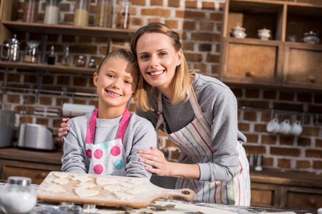 mom with her kid baking in the kitchen and smiling.