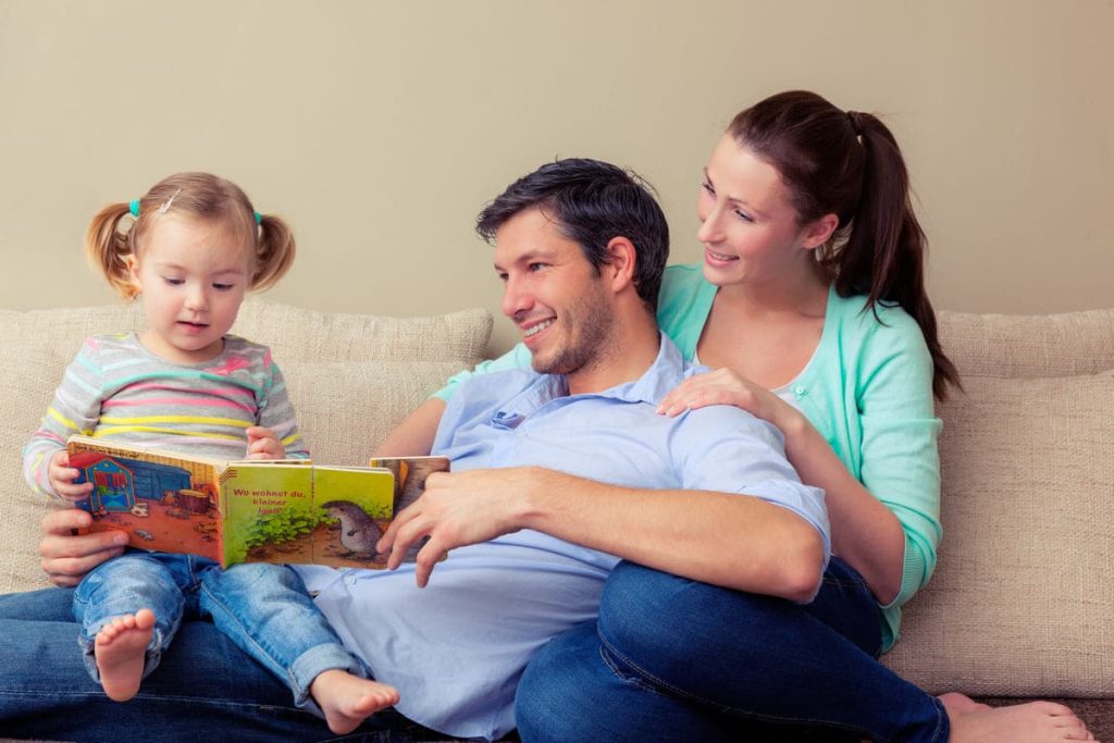 parents reading with their daughter.