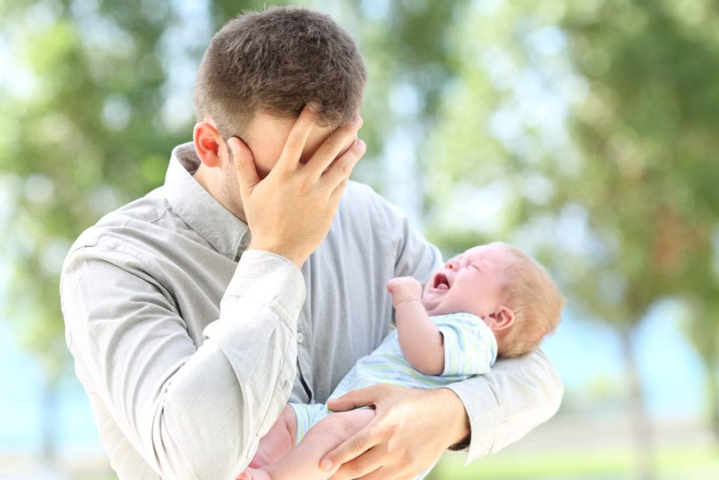 A dad holding a baby while crying.