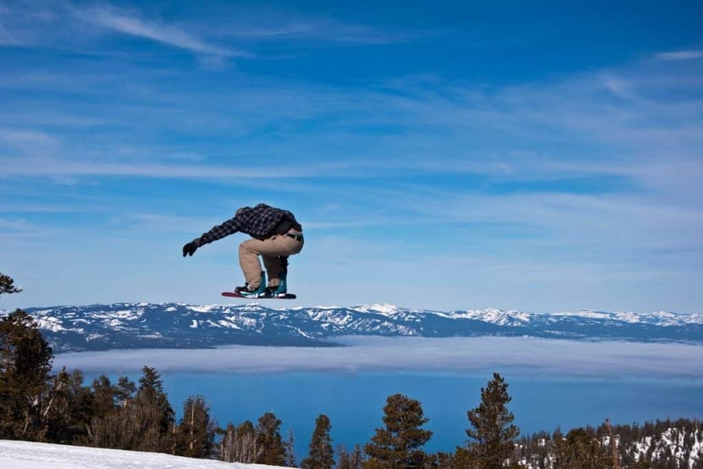 A snowboarder jumps over mountains and Lake Tahoe, California.