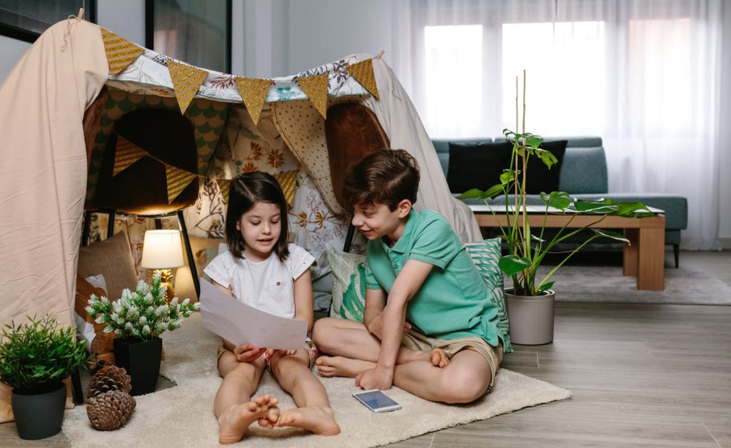 Boy and girl playing in a diy tent at home.