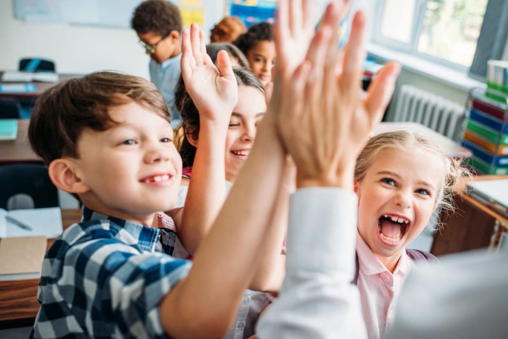 Kids giving high five to the teacher.