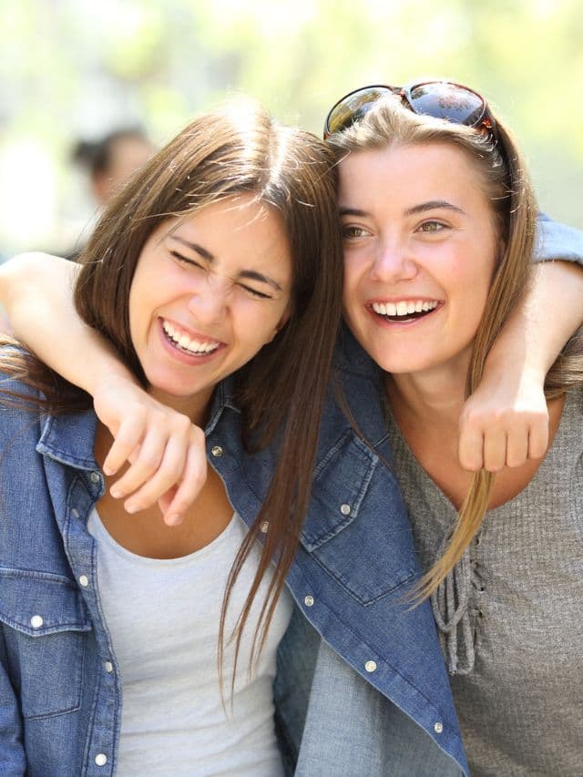 Two friends laughing loud in the street.