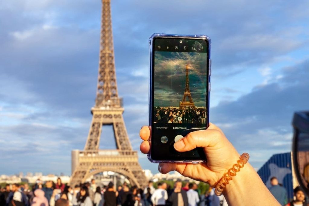 a hand taking a photo of eiffel tower.