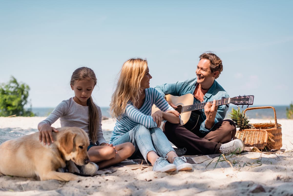 family playing guitar on the beach.