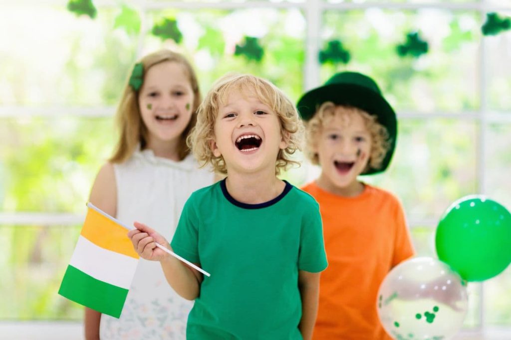 Family celebrating St. Patrick's Day. Irish holiday, culture and tradition. Kids wear green leprechaun hat and beard with Ireland flag and clover leaf.