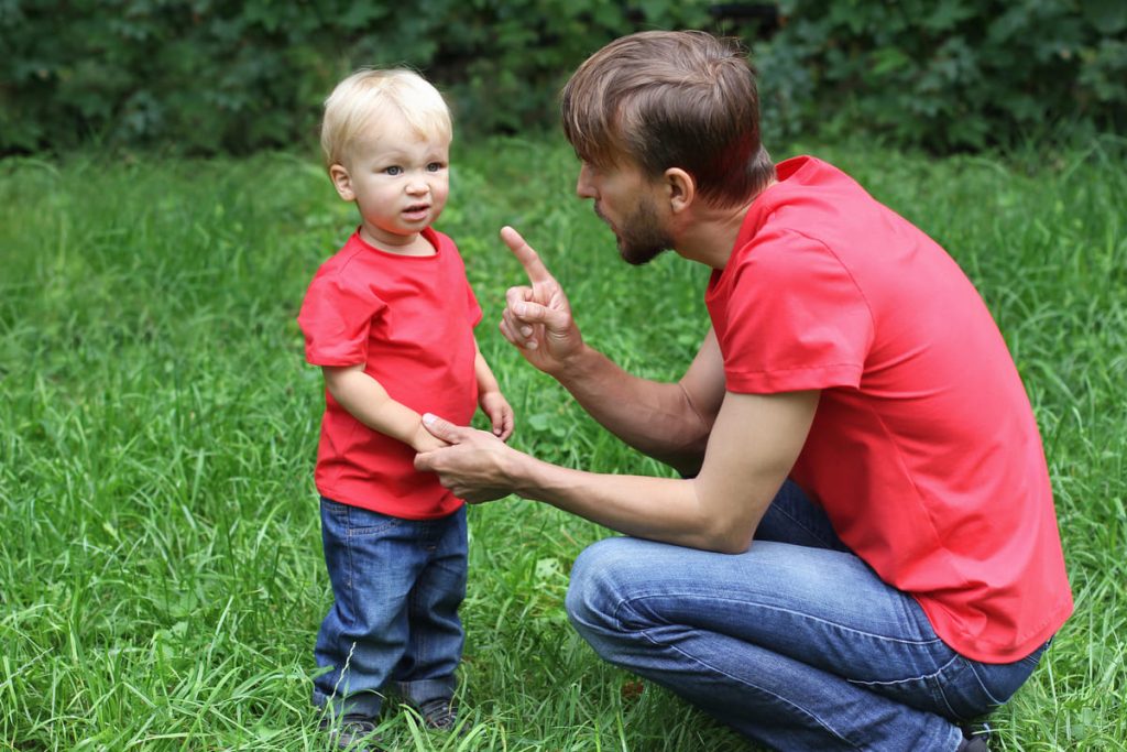 Father talking to son in a grass field.