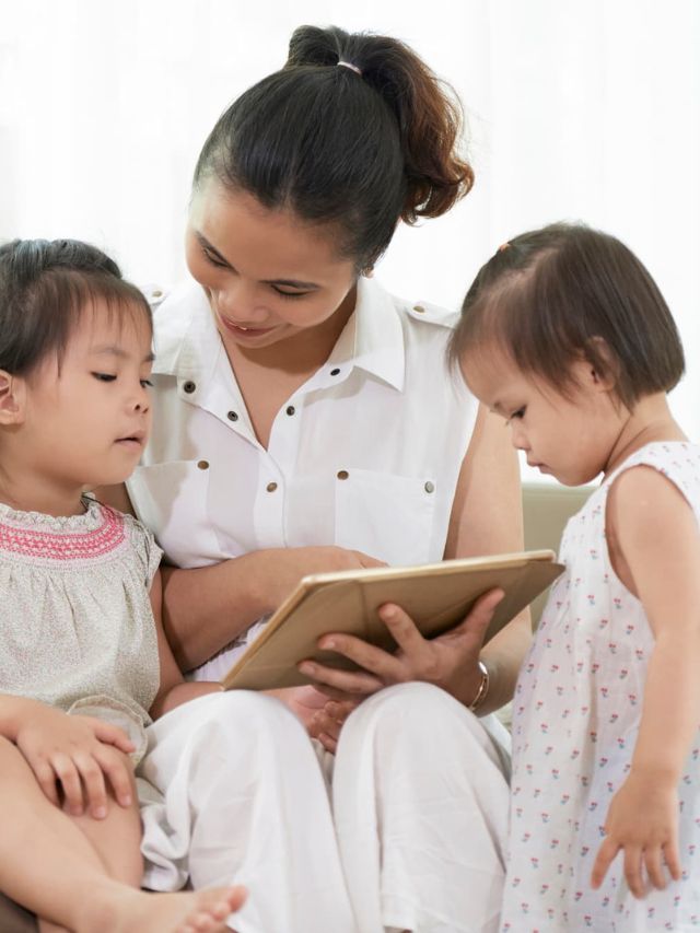 Mother showing movie on tablet to her toddlers.