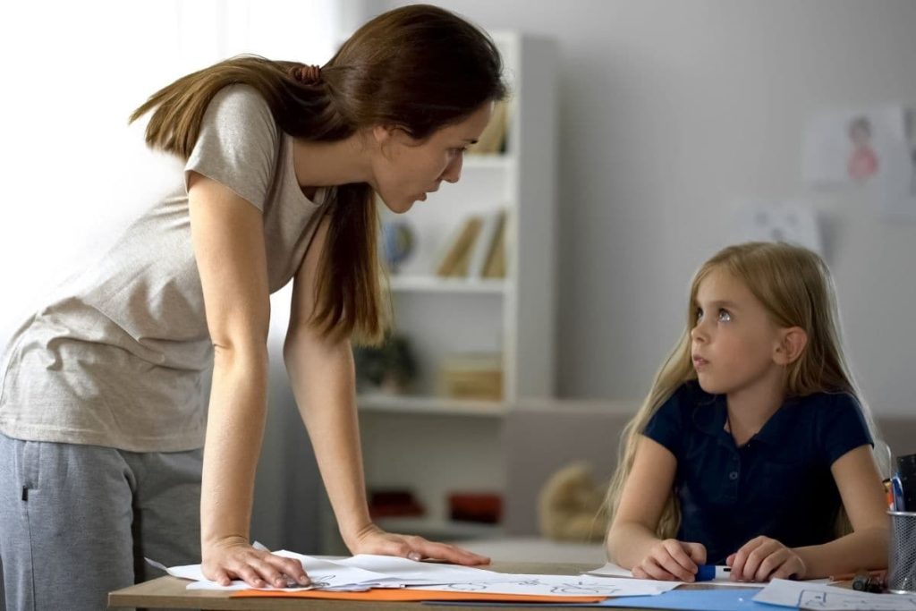 Strict mother criticizing little daughter for drawings, stressed childhood.