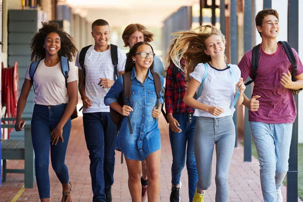 Teenager school kids running in high school hallway.