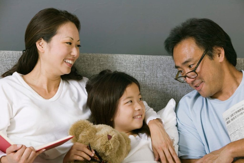 an asian-japanese family happily smiling and having conversation in a sofa at home.