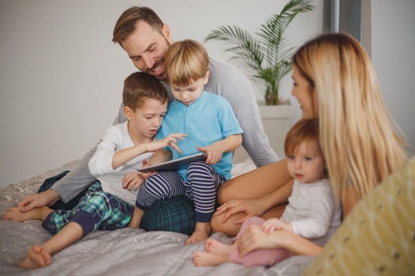 parent with three kids together looking at an ipad.