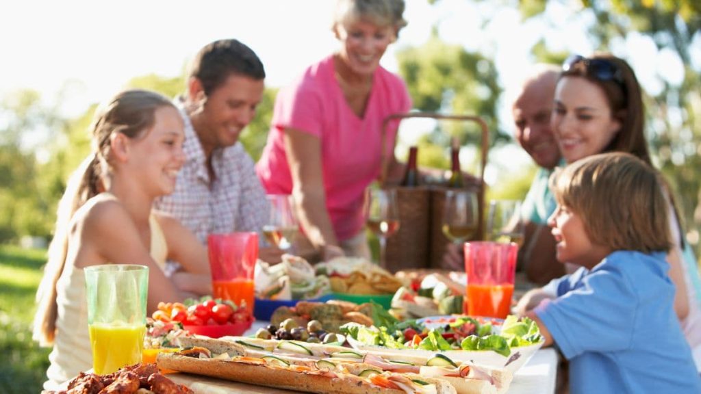 family eating healthy food outside picnic.