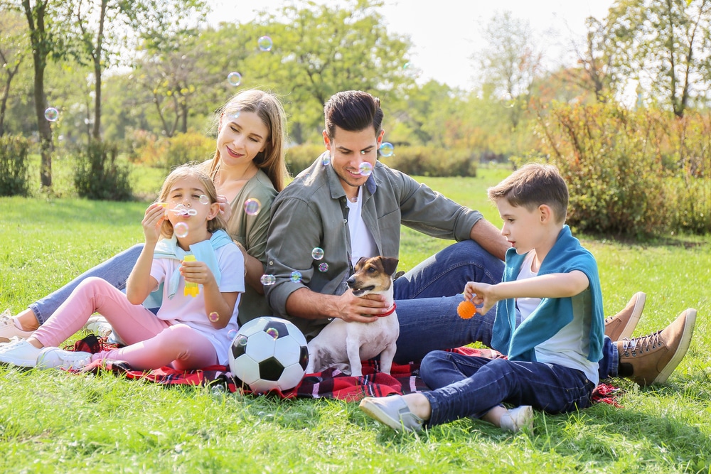 family of four with a dog outside.