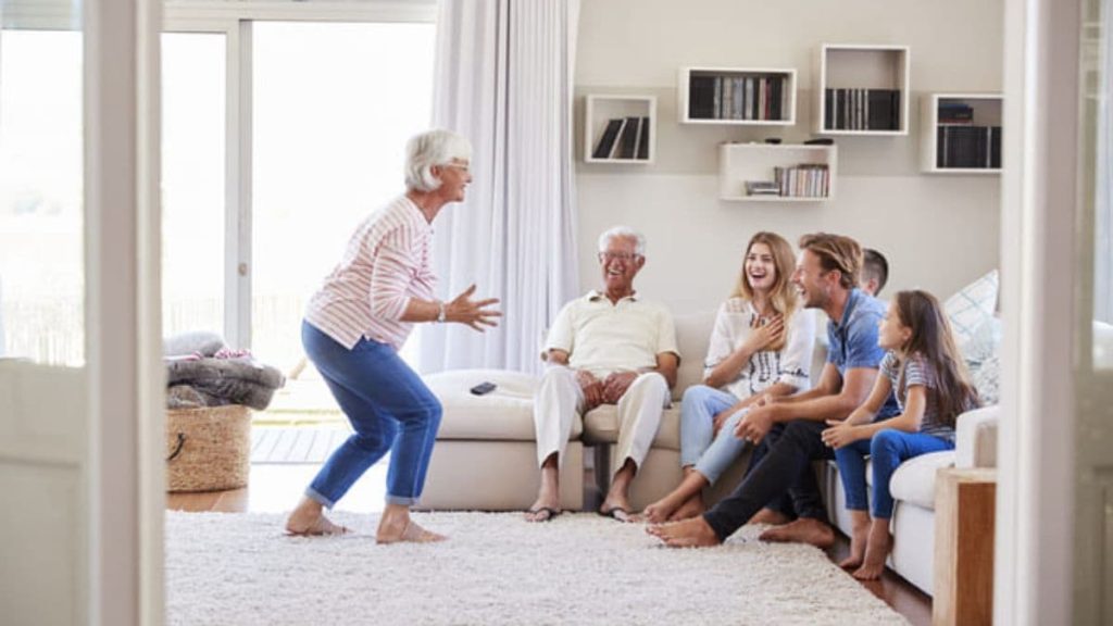 family with grandparents doing charades in the living room.