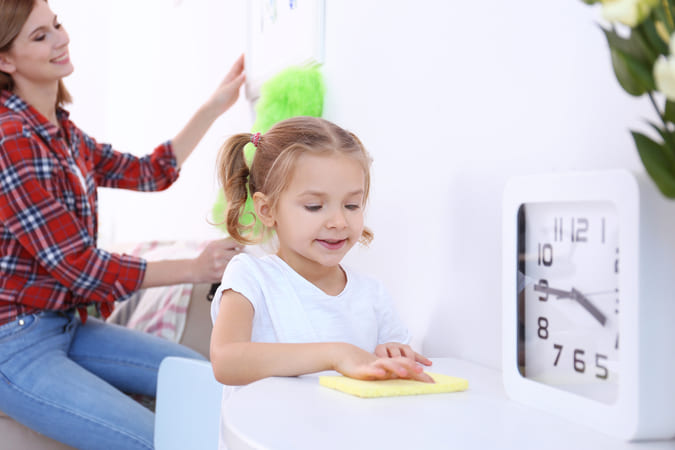 girl helping her mom by wiping the table.