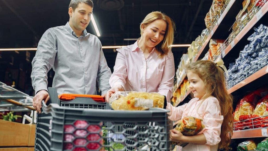 parent with a kid in the grocery store with a cart.