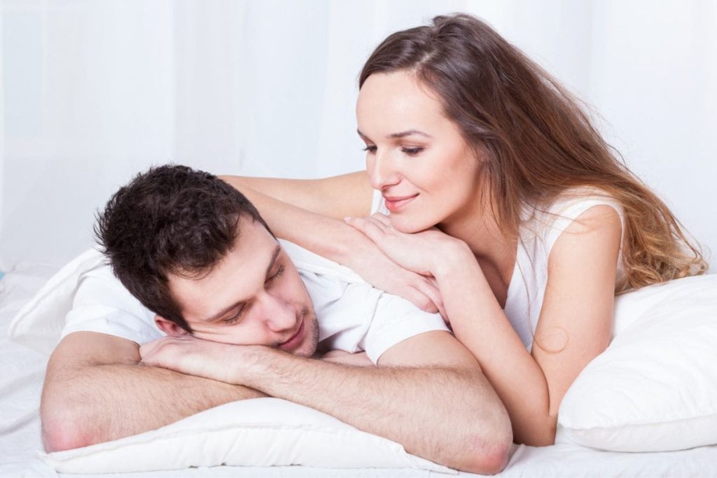 lovers cuddling in white bed.